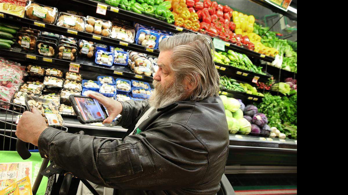 
Mike Hansen uses a tablet to scan the bar code on mushrooms at the Piggly Wiggly in Mayville, Wis. The store uses the Fetch Rewards app, which gives customers savings and loyalty points and provides data to the grocer. 
