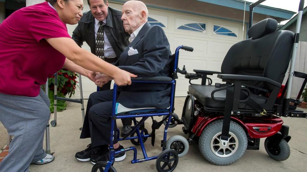 With the joy ride over, care giver Andriana Castro helps Alvin Butcher back into his more conventional wheel chair as Chaplain Roger Rustad looks on.