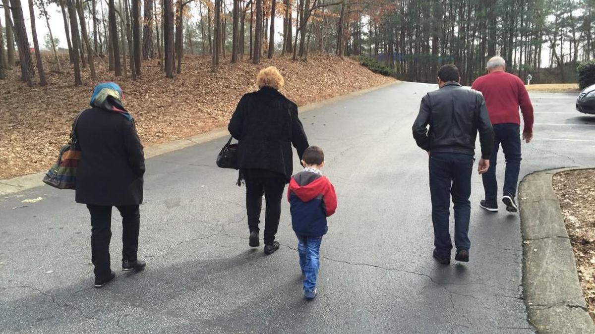 Jim and Jeanne Slaughenhoup, volunteers with Johnson Ferry Baptist Church in Marietta, Ga., lead Hasan and his parents, Syrian refugees, to the school Hasan will be attending.
