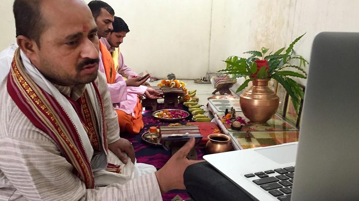 Priest Narayan Shastri, left, conducts a puja via Skype for the Shubhpuja company in Noida, India.