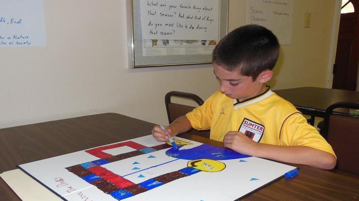 
Wyatt Eckhardt, 8, colors in the water on the board game he created called Survive the Docks. Eckhardt used what he learned about sharks and eels in school to come up with the concept for the game he made during a Young Writers’ Academy summer camp at the Anne Springs Close Greenway.
