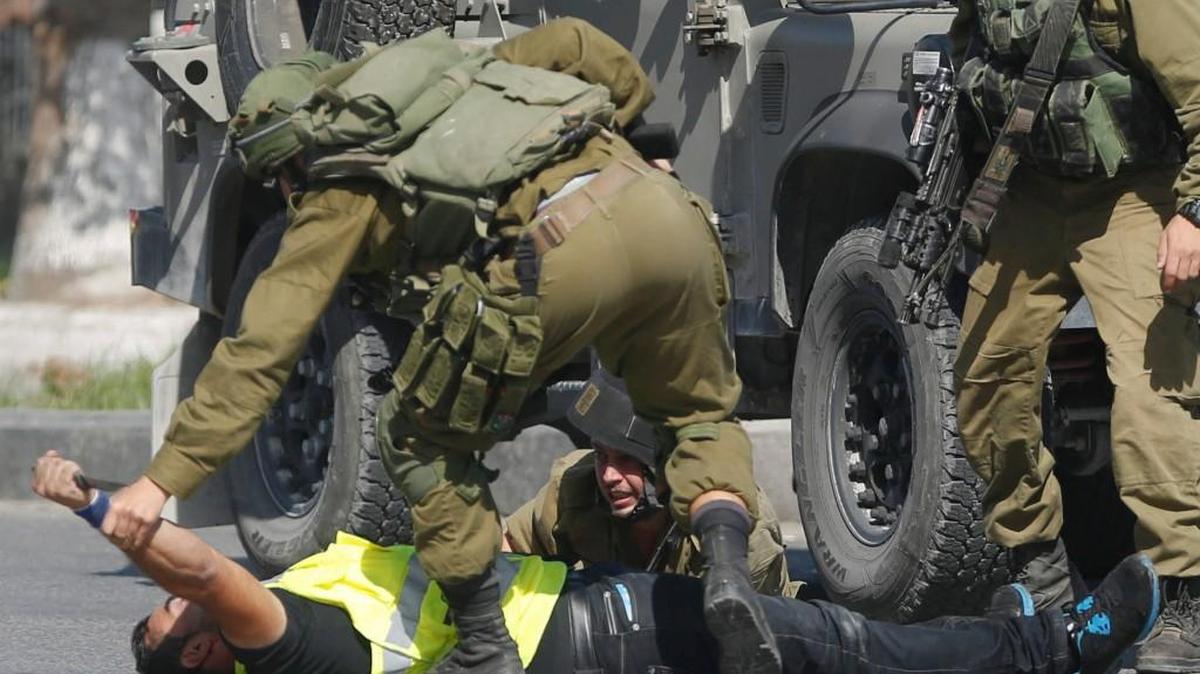 An Israeli soldier grabs a Palestinian’s hand holding a knife after he stabbed another Israeli soldier, on the ground, during clashes in Hebron, West Bank on Friday. The Palestinian man wearing a yellow “press” vest and a T-shirt identifying him as a journalist stabbed and wounded an Israeli soldier before being shot dead by troops, the latest in a monthlong spate of attacks.