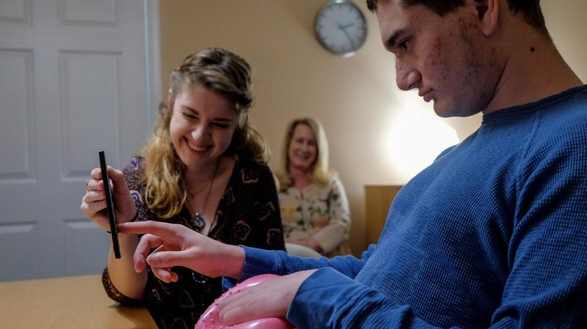 Therapist Meghann Parkinson blushes as Gordy Baylinson, who has autism and is nonspeaking, writes kind words about her as Elizabeth Vosseller, the director of the center, sits by during a therapy session on Wednesday at the Growing Kids Therapy Center in Herndon, Va.