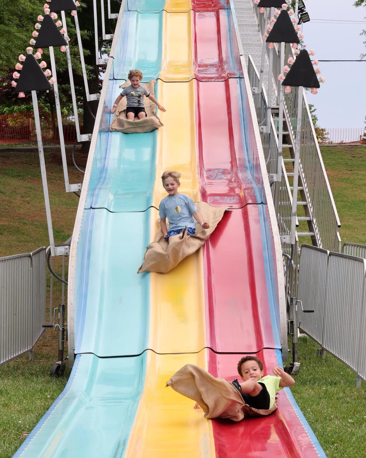 Children fly down a large slide Friday, May 2, 2025 at Fort Mill’s Strawberry Festival.