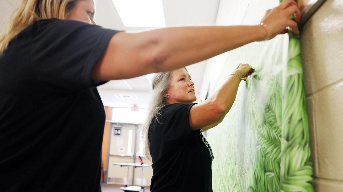 Windy Sizemore, right, and Jessica Mills put up a bulletin board outside a fourth grade classroom Friday at Harold C. Johnson Elementary School in York. The first day of school is Aug. 1.