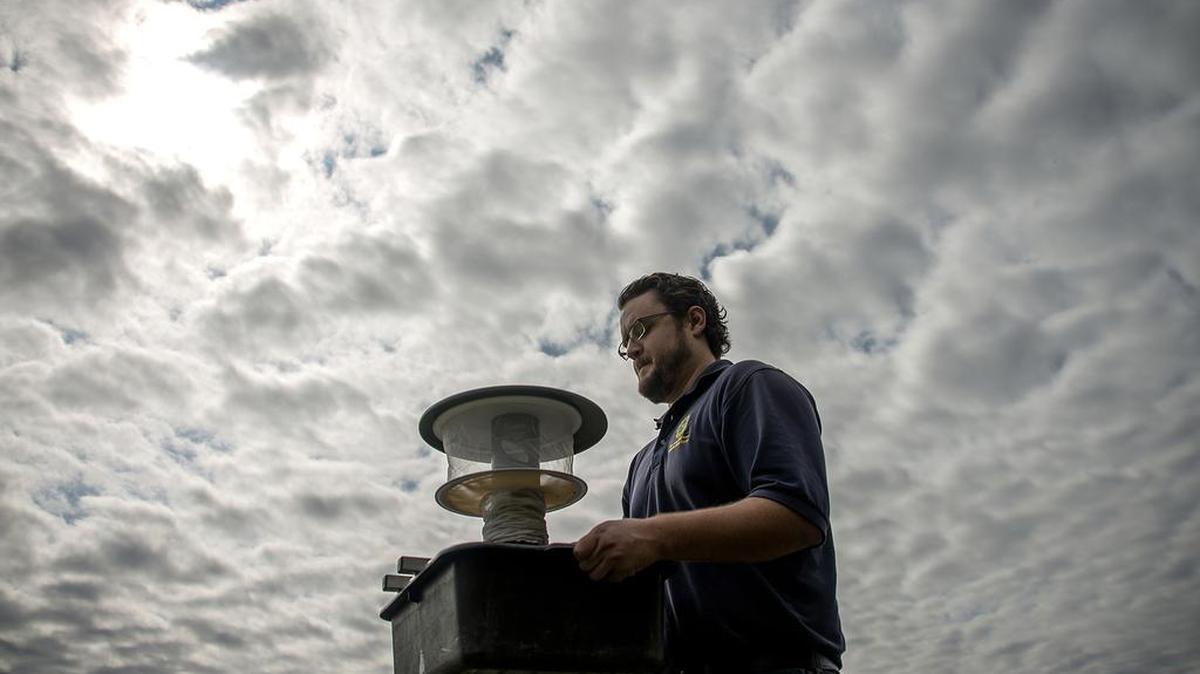 Microbiologist Spencer Lockwood carries a mosquito trap in Dallas. The trap is comprised of a tub for stink water, a small suction fan, a mosquito net and a small battery for powering the suction fan.