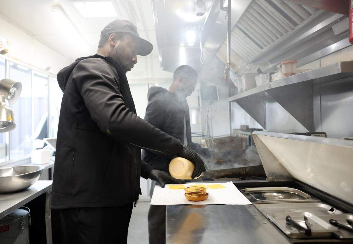 Joel Lutuangu, left, and Magloire Lubika make smash burgers Thursday at their Surefire food truck near uptown Charlotte.