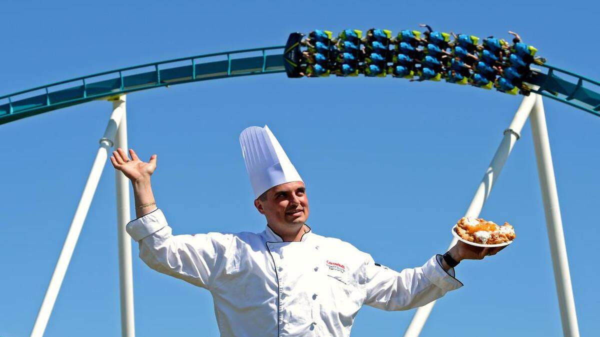 
Krzysztof Siuta, Executive Chef at Carowinds, holds a peaches and creme funnel cake as Fury 325 roller coaster passes overhead. Siuta has overseen new food offerings at Carowinds that include chicken and waffles, red velvet funnel cakes, fun fries, shrimp and grits, brisket and pulled pork. 

