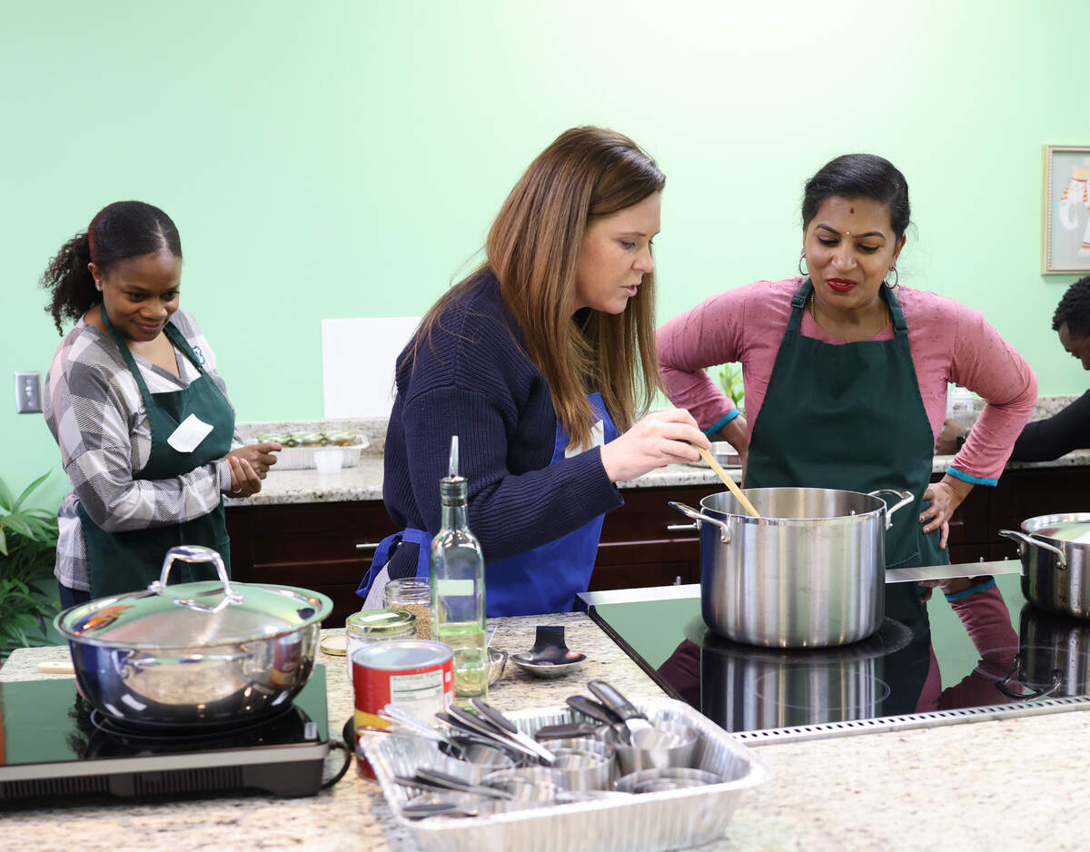 Chelle Keough, middle, talks to instructor Santhoshi Radhakrishnan as Bakahri Baldwin watches at a cooking class at Santhoshi’s Kitchen in February.
