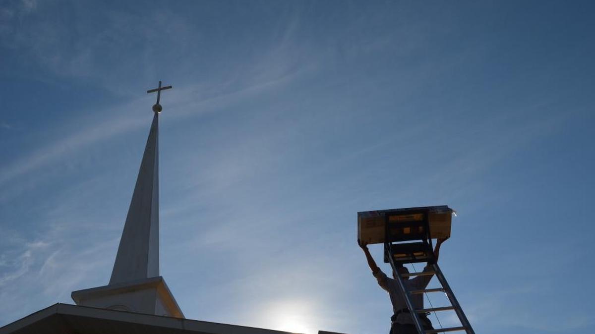 A member of the Carolina Ninja Windows and Roofing crew takes a pack of shingles off the lift on the roof of the Common Ground Baptist Church.