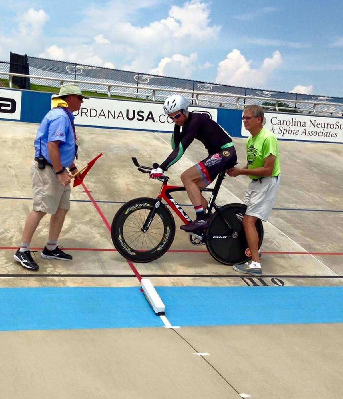 Mack Bailey, right, holds a rider before he starts his lap at the of2015 USA Cycling Masters Track National Championships at the Giordana Veldrome in Rock Hill. 