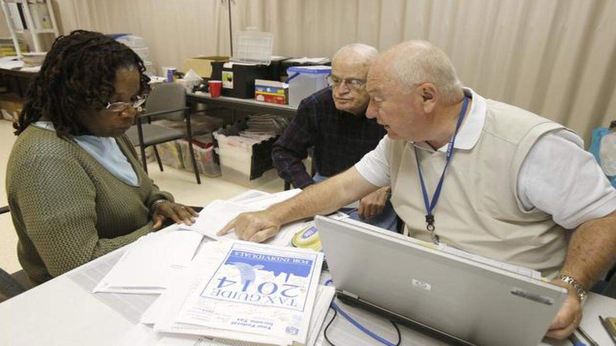 
Volunteers doing taxes at the Wellness Center on the first floor of City Hall in Rock Hill. Bill Perry, right, goes over a tax return with Rocksanna Barnette, left, on Thursday. Larry Sams, center, prepared Barnette’s tax forms.
