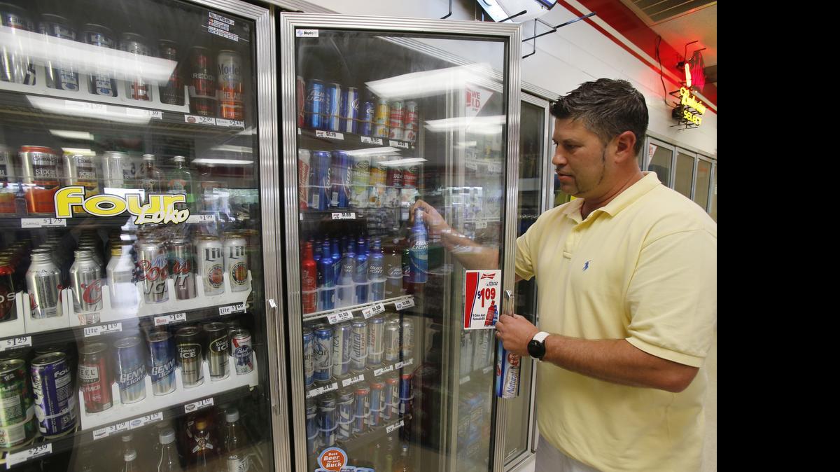 
Brian Brownell, a part-time employee at Camp Creek Grocery in Lancaster, examines the store’s beer coolers.
