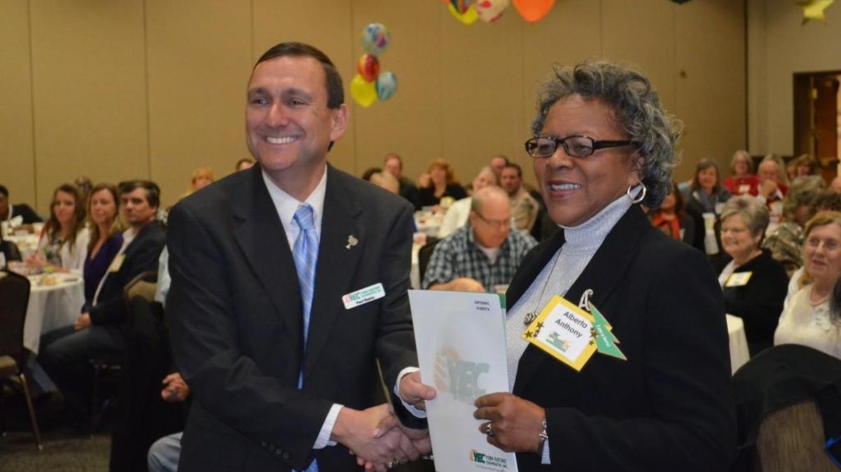 Paul Basha, president and CEO of York Electric Cooperative shakes hands with Alberta Anthony, who taught in York schools for 40 years.