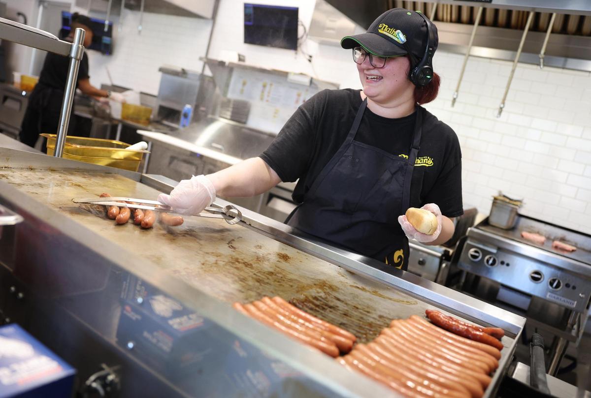 Kelsi Crisp grills hotdogs Friday at Nathan’s Famous in Rock Hill. It’s one of a number of restaurants that have opened in the area recently.