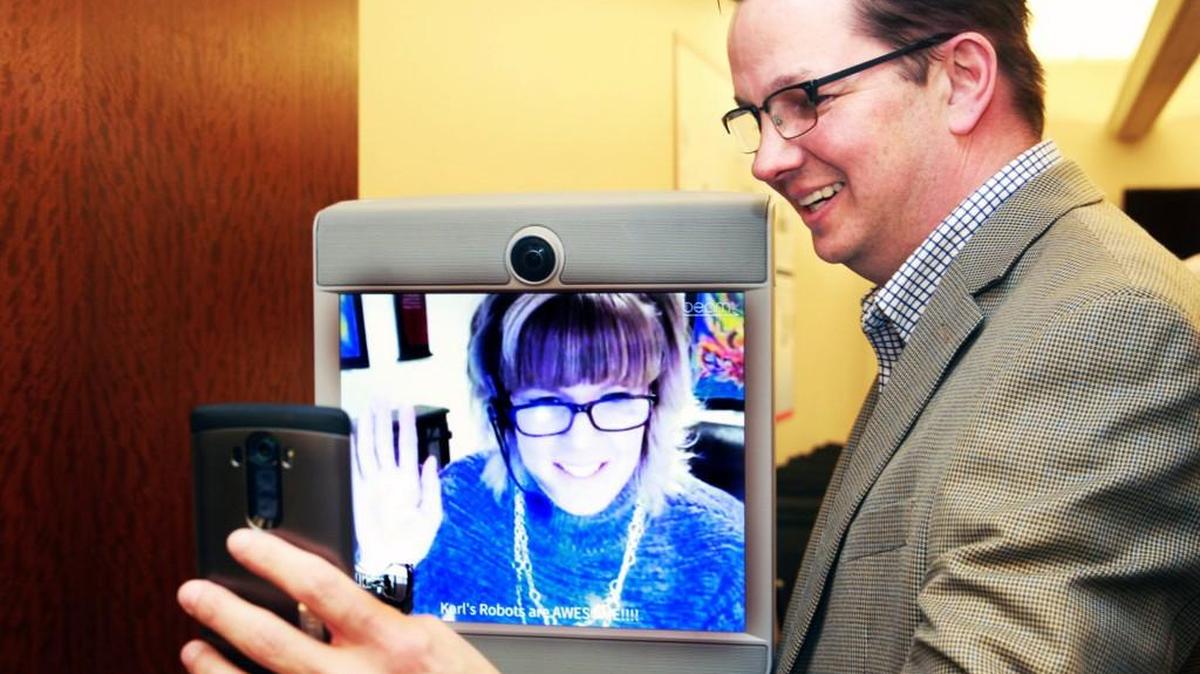 Amy Lamb, an app development consultant at Northwestern Mutual, on screen, uses a robot that she controls from home to attend meetings at the office. Lamb’s manager Tom Mullen takes a selfie of the two of them following a meeting.