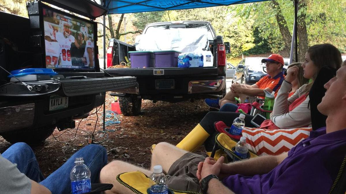 Tailgating fans watch a television that is secure in a TOC Box.