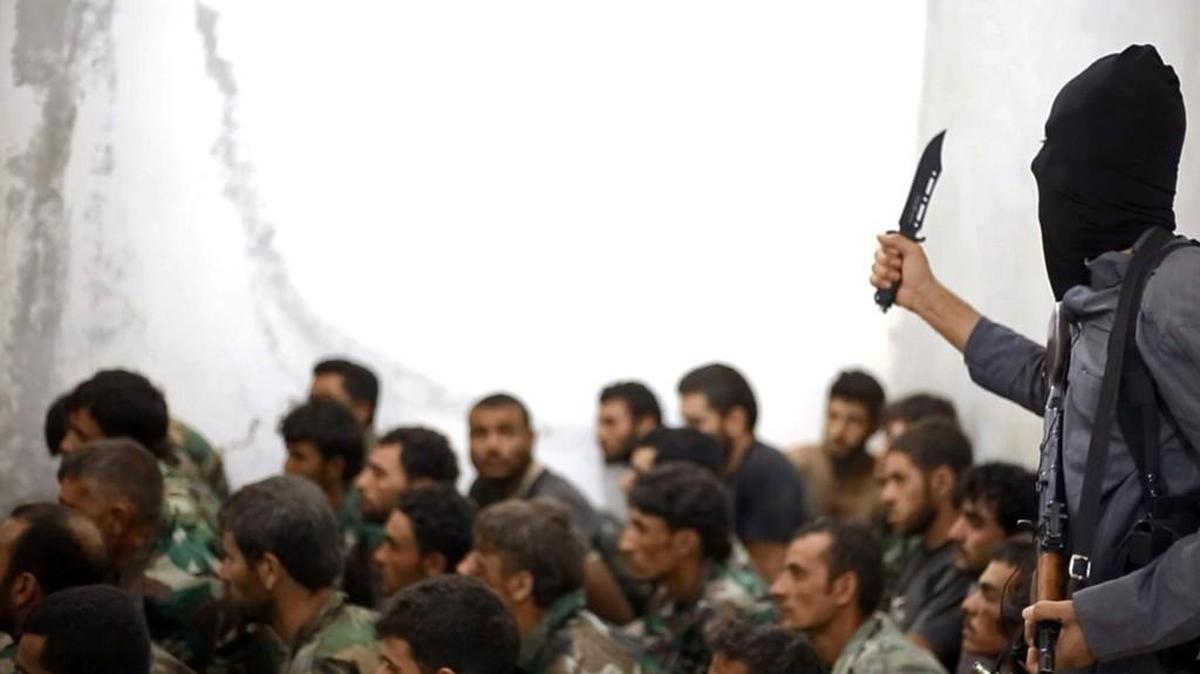 A fighter from the Islamic State group, armed with a knife and an automatic weapon, next to captured Syrian army soldiers and officers, following the battle for the Tabqa air base in Raqqa, Syria.