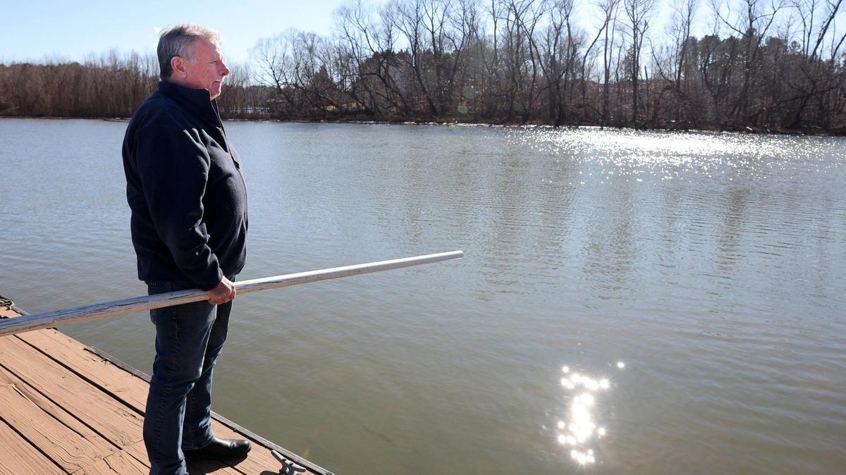 Armed with a pole to determine how deep the water is near his Lake Wylie home Tuesday, Ed Lindsey looks out at the silt that has formed in the water. Many Lake Wylie residents want a new dredging company to be allowed on the lake, to remove sediment.