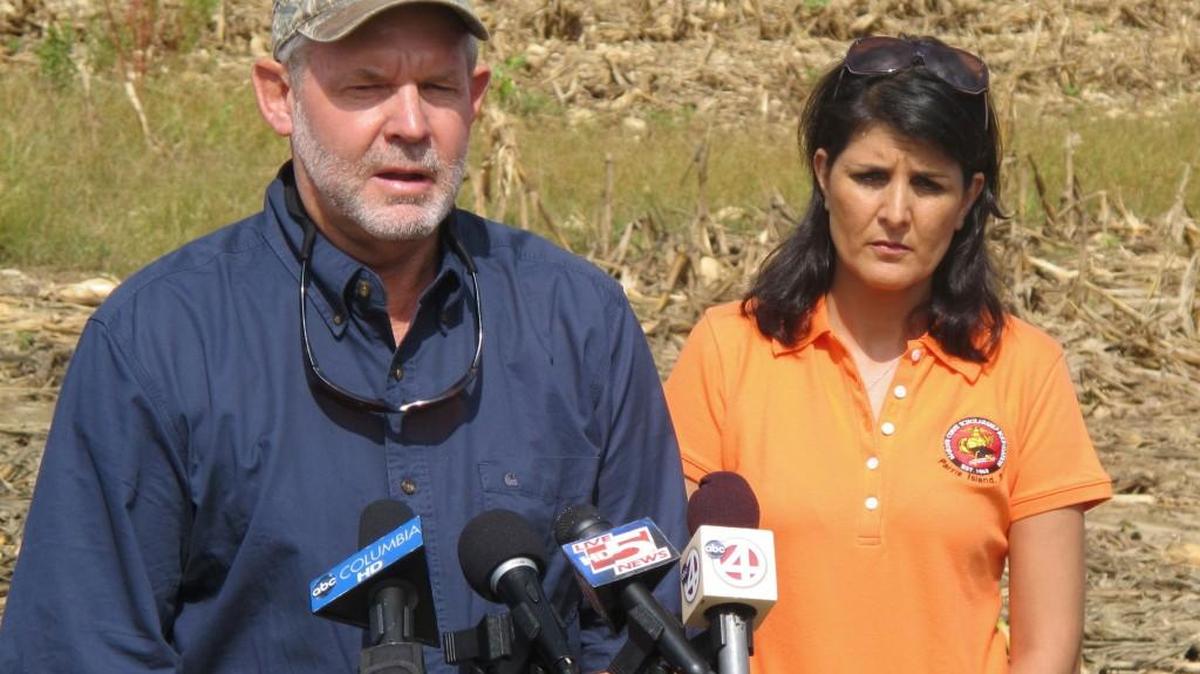 FILE - In this Aug.19, 2013 file photo, farmer John Pendarvis, with South Carolina Gov. Nilkki Haley looking on, discusses the effect of the heavy rains on farming during a news conference at his farm outside Harleyville.