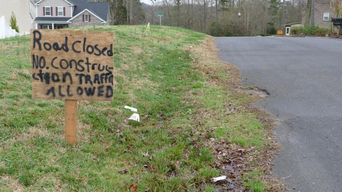 A handwritten wooden sign on Convention Drive announces the private road has been closed to construction traffic. Property owner Earl Coulston cut off access to a York County construction project on Sugar Creek.