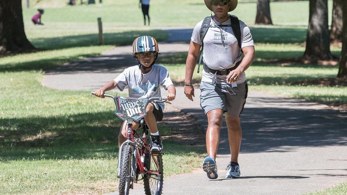 Mandile Young walks around Walter Elisha Park behind his son Carson last summer. On Friday, the Rock Hill-Fort Mill Area Transportation Study will vote on a new pedestrian and bicycle lane program.