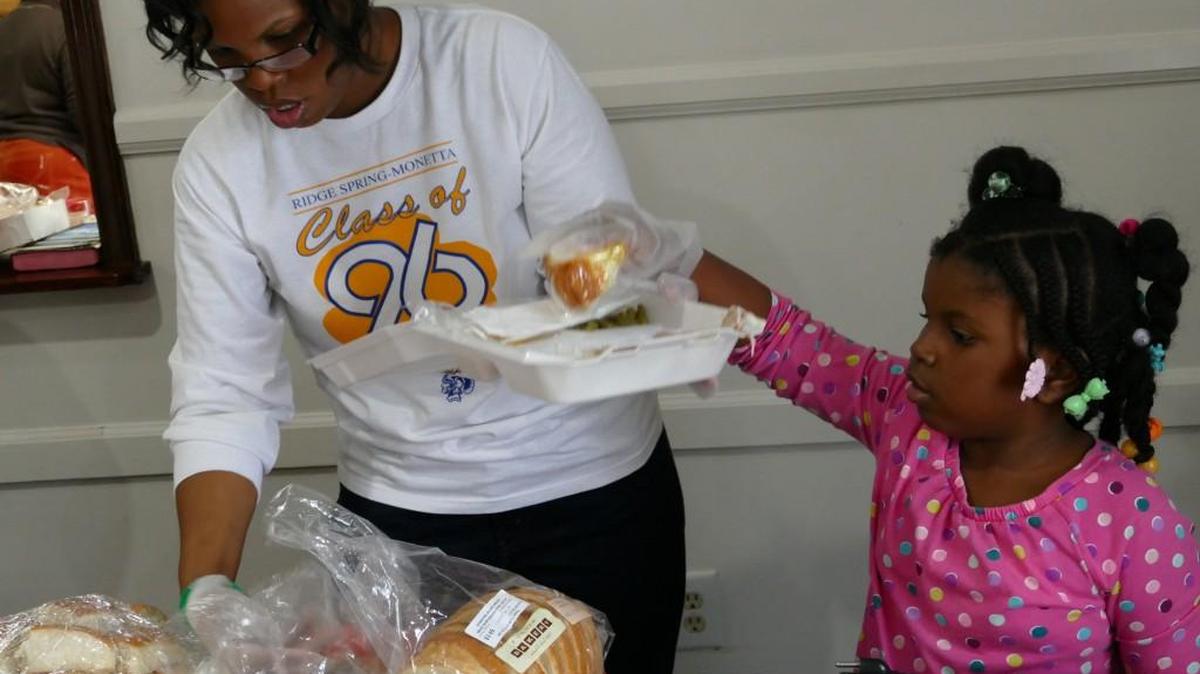 6-year-old McKayla Sumter adds a piece of cake as a finishing touch to a plate prepared by volunteer Melody Sumter at Flint Hill Baptist’s Christmas Eve dinner.