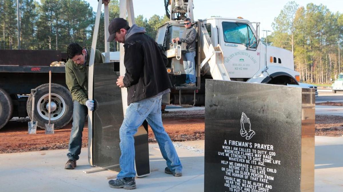 Daniel Gaulden and Dewain Vincent position a piece of the monument as the World Trade Center memorial gets a new home at the new York County fire training center near York.