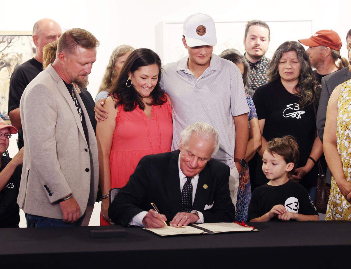 S.C. Gov. Henry McMaster ceremoniously signs Gavin’s Law, which creates felony offenses of sexual extortion and aggravated sexual extortion. Family of the law’s namesake, Gavin Guffey, are from left, Gavin’s father Brandon Guffey, mother Michelle Guffey and brothers Coen Guffey and 5-year-old Callahan Guffey stand around McMaster.