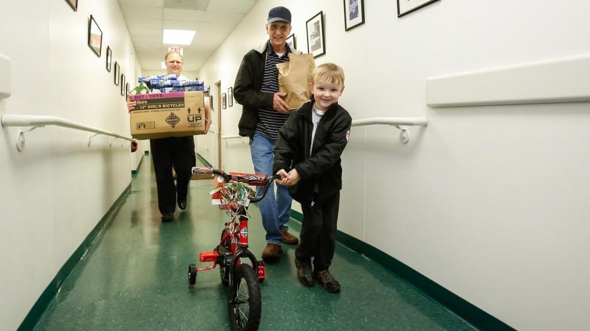 Colin McCoy proudly wheels his new bike out to the car with his grandpa John Perrine.