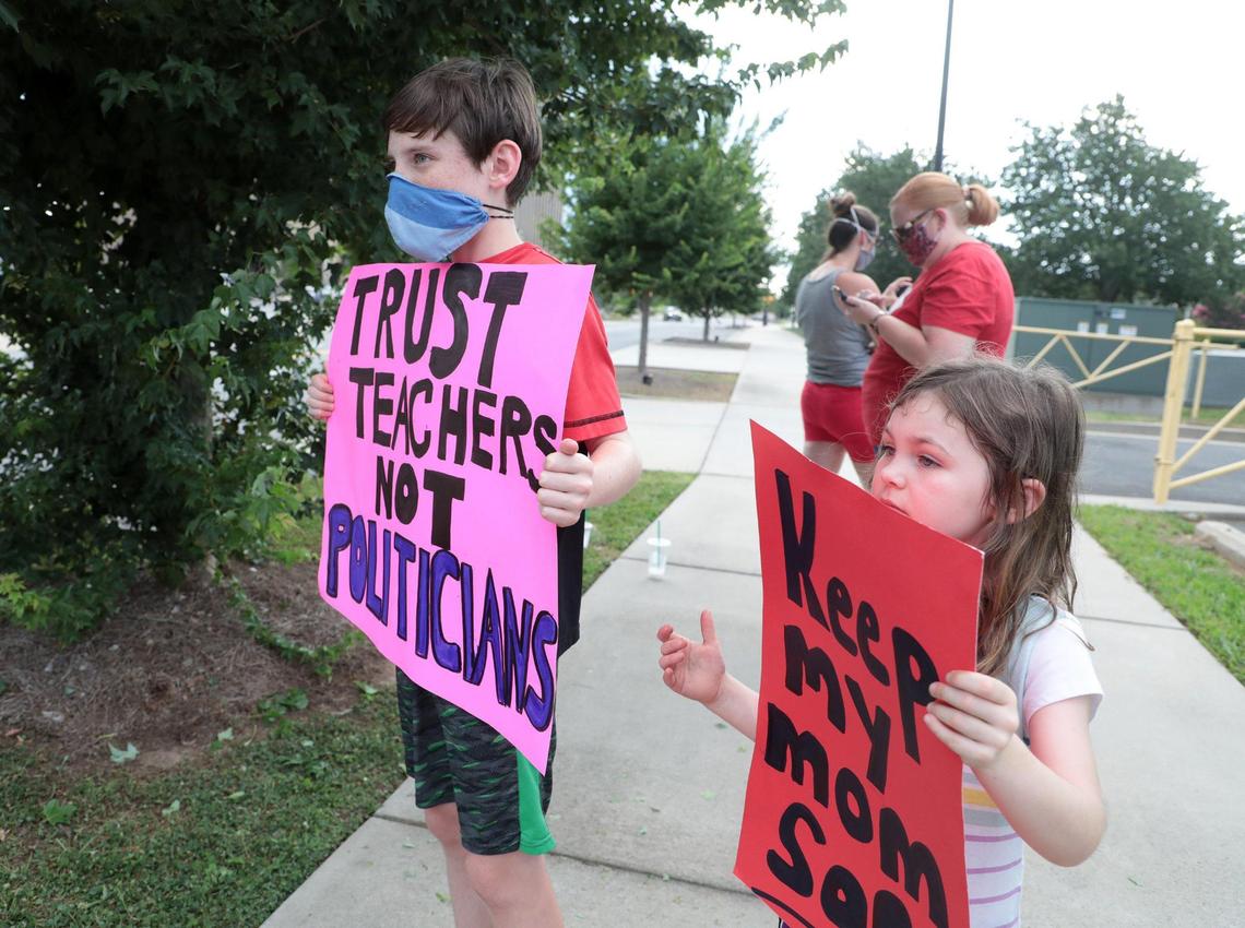 Children hold signs outside a Rock Hill school board meeting Thursday.