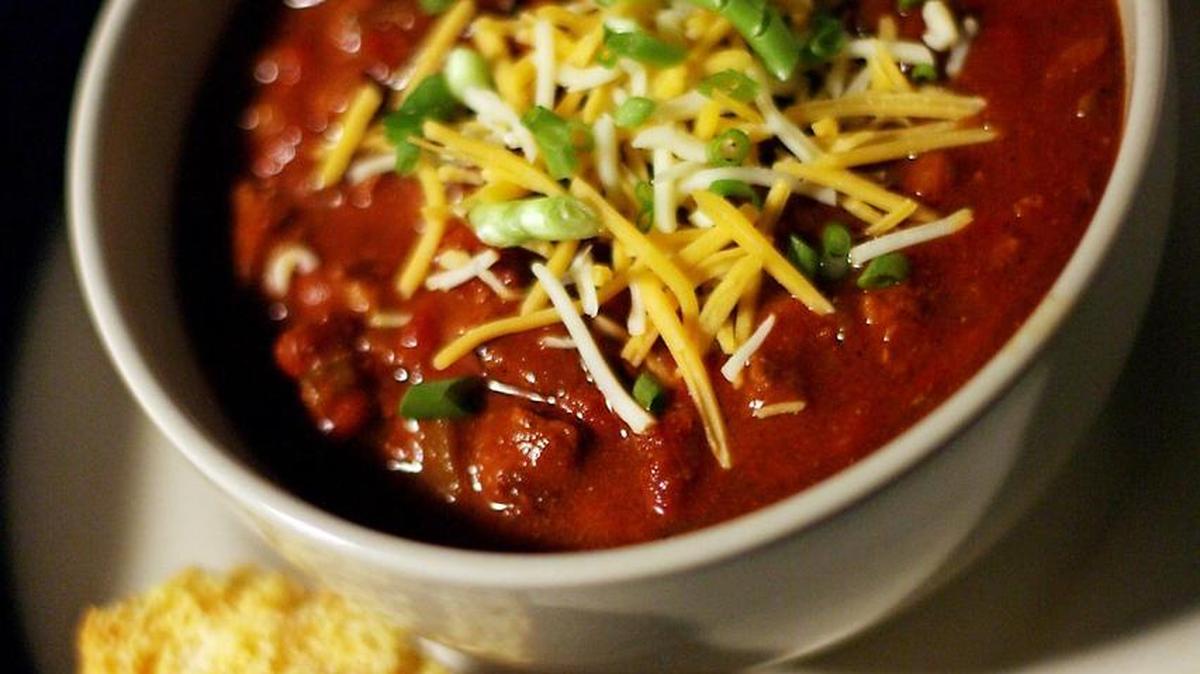 Chili garnished with cheese and scallions and served with a side of cornbread is perfect for a cold winter night.