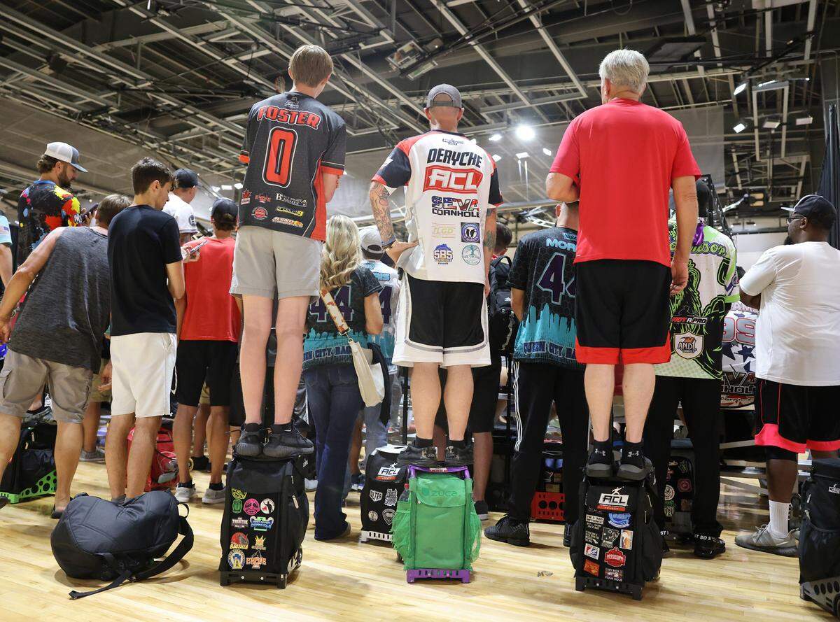 Cornhole enthusiasts stand on their bags to watch a match Friday at the American Cornhole League World Championships.