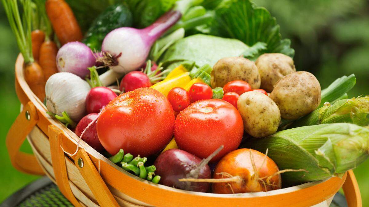 A basket filled with fresh vegetables from a garden.