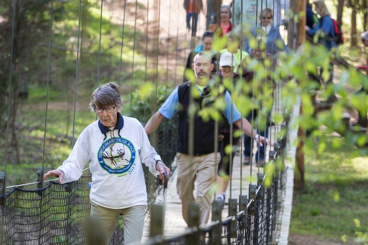 In this file photo, the late Anne Springs Close leads a 3-mile hike in celebration of Earth Day. The swinging bridge over Steele Creek will be replaced by next spring.