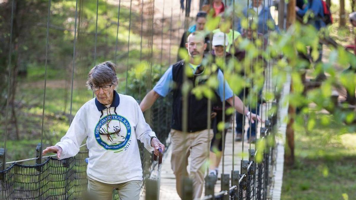 In this file photo, the late Anne Springs Close leads a 3-mile hike in celebration of Earth Day. The swinging bridge over Steele Creek will be replaced by next spring.