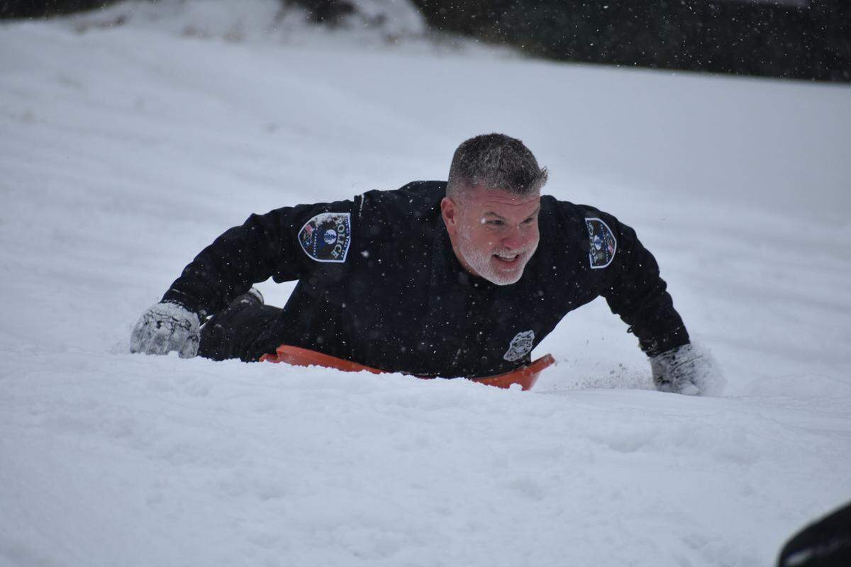 Tega Cay Police Chief Joey Crosby sleds down a hill Saturday as snow falls throughout the Rock Hill region.