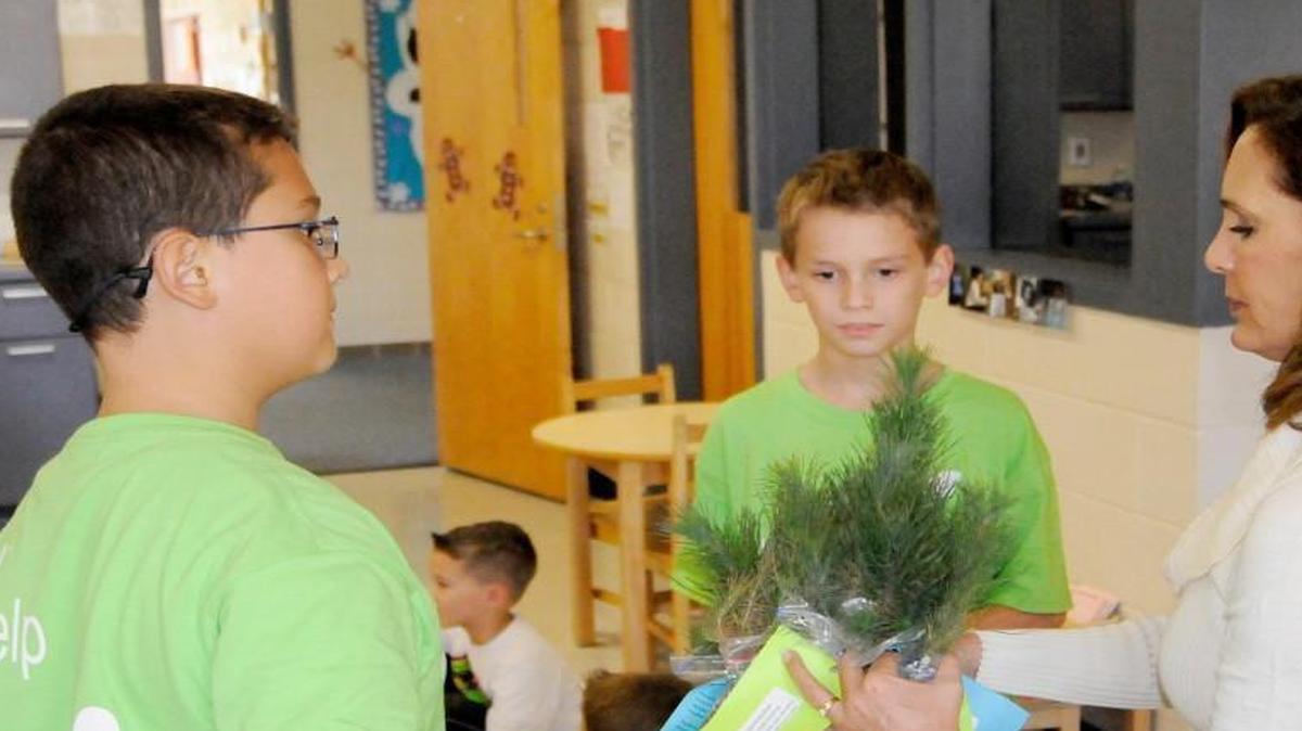 Dylan Carroll, left, and Jaden Romero give Virginia pine seedlings to teacher Linda Mullikin at Hunter Street Elementary School in York to observe Arbor Day.