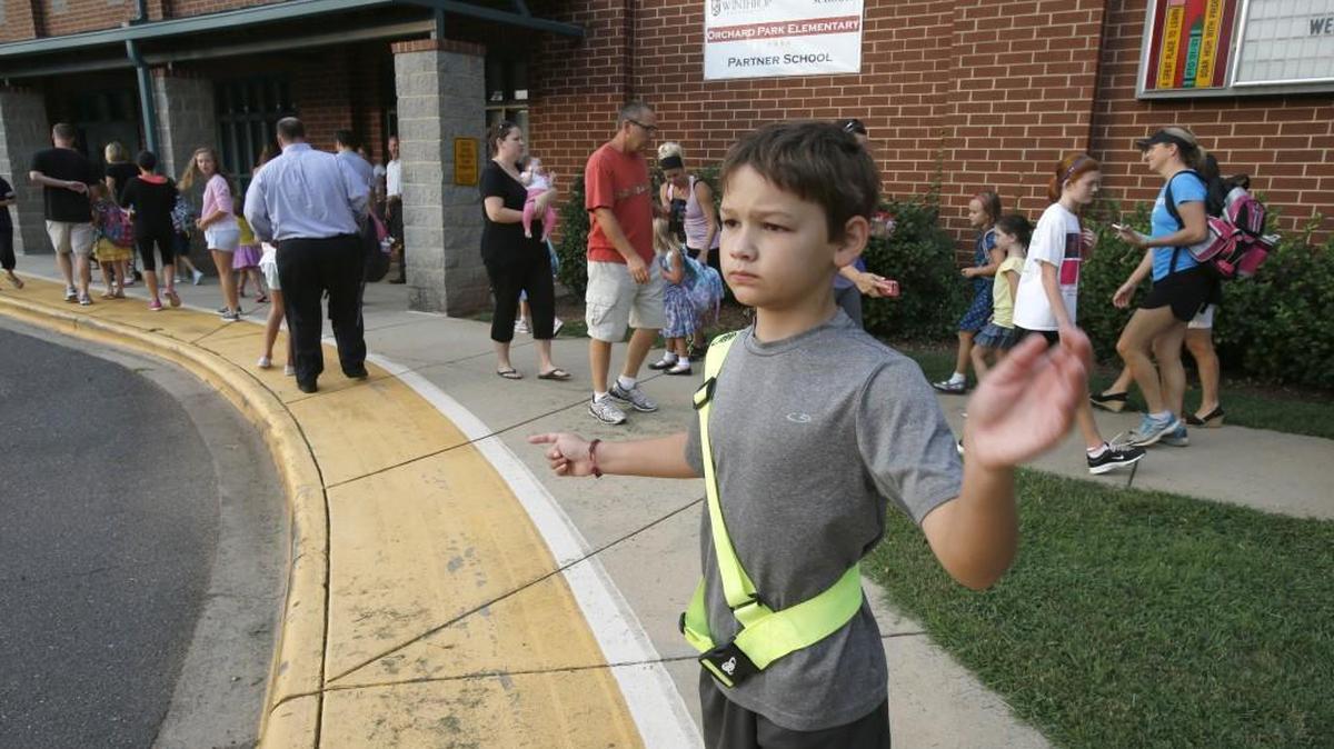 At Orchard Park Elementary in Fort Mill, student and safety patrol member Zachary Nastiuk directs cars on the first day of school last year. OPES is one of four schools that will have private security protection when the 2016-’17 school year begins.