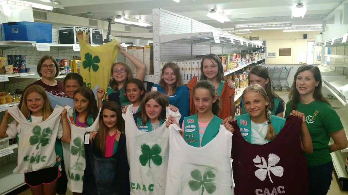 Girl Scouts from Troop 722 Lake Wylie (Hornets Nest Council) hold up the reusable T-shirt shopping bags they made for Clover Area Assistance Center food pantry.