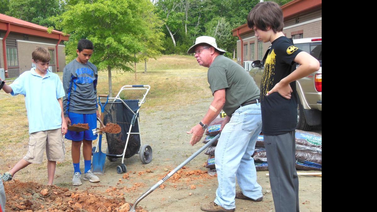 
York County Master Gardener Rolf Mischker shows seventh-graders, from left, Aaron Spearman, Petey Tuipulotu and Westin Alps at Springfield Middle School the best technique to shovel topsoil. The students are part of a group building three large raised garden beds to plant produce to study science, as well as learn where their food comes from.

