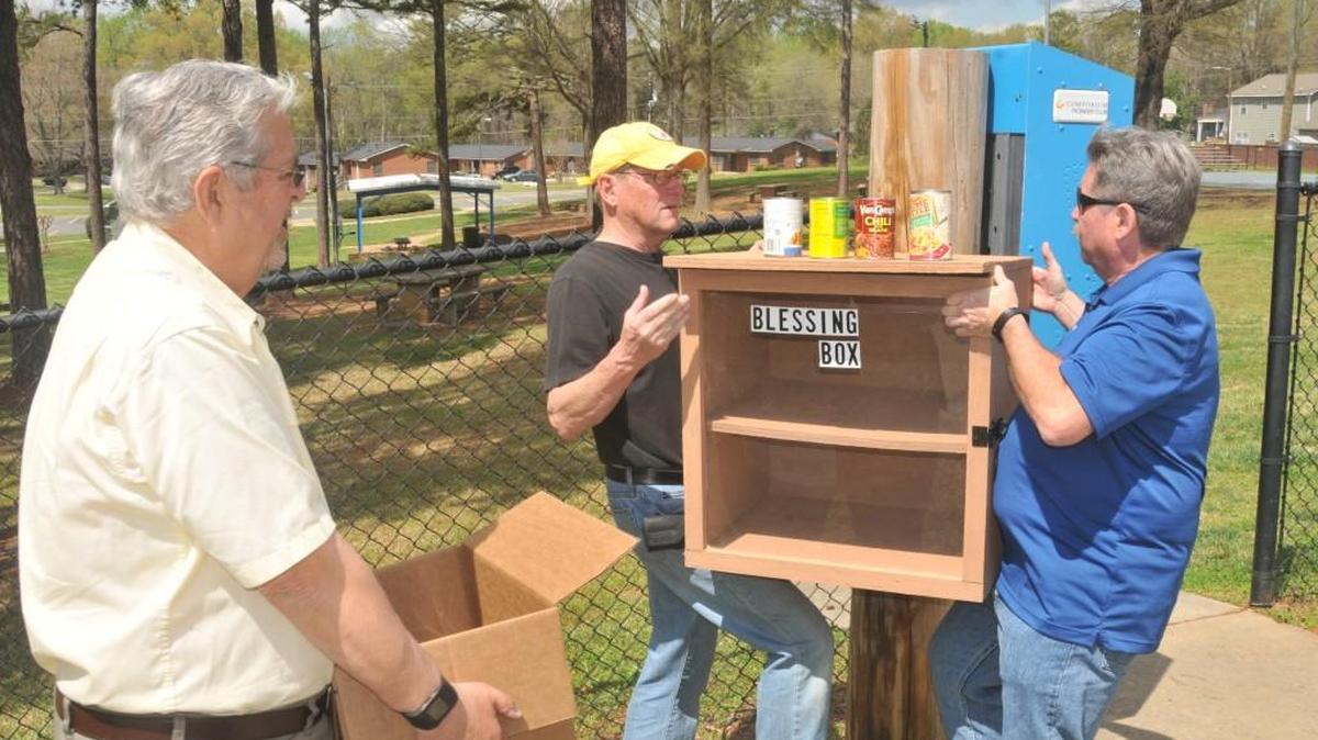 Frank DeLuise, Gary Hill and Keith Sterling position a Blessing Box between Greater Bethlehem Baptist Church and Steele Street Park.