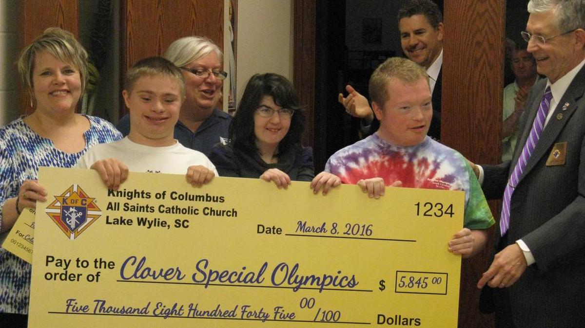 Patti Myers, Clover Area Special Olympics coordinator, left, along with colleagues and Special Olympics athletes, receives a check from Grand Knight Rick Engel, right, of the Knights of Columbus All Saints Council.