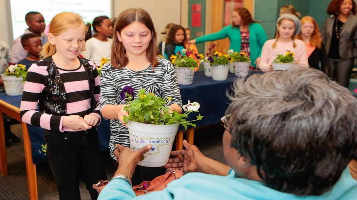 Kathrine Bowman and Ella Kate Bence deliver a flowerpot to a resident of the Paradise neighborhood as Fort Mill Elementary School students partner with Habitat for Humanity to spread Thanksgiving cheer.