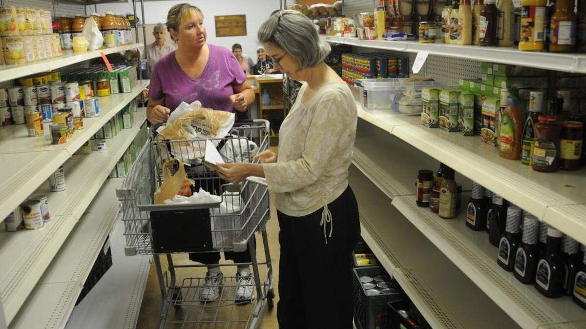 Client Cathy Cook and volunteer Julie Young peruse the new pantry setup at Clover Area Assistance Center. New living basics classes are being piloted in June and July at the Center.