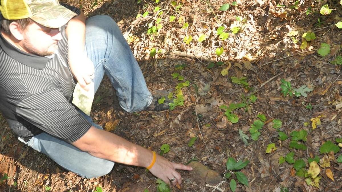 Matt Burton of Lake Wylie points to what he believed is a grave marker on the development site for Lake Crest.