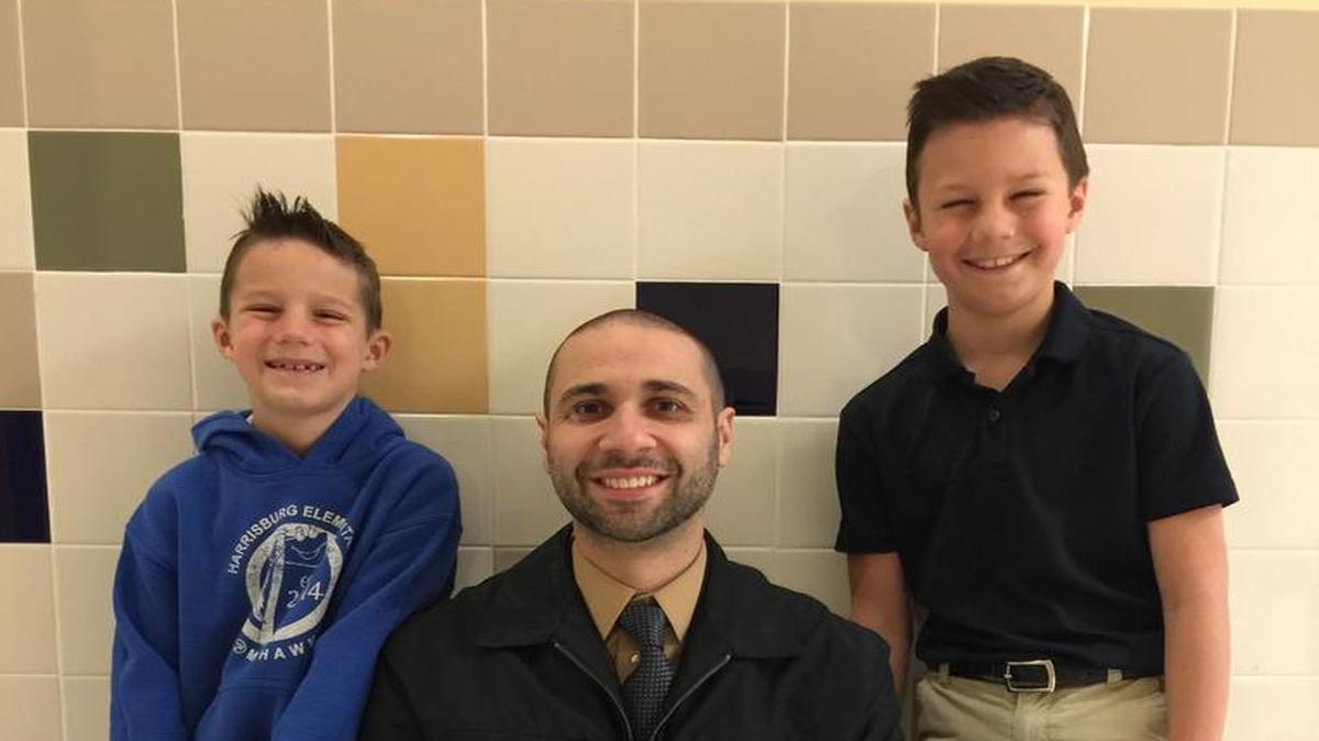 Principal Steve Puckett is flanked by brothers Bailey (left) and Brady Kochan. Their mother posted an inspirational letter Puckett sent home with students to Facebook.