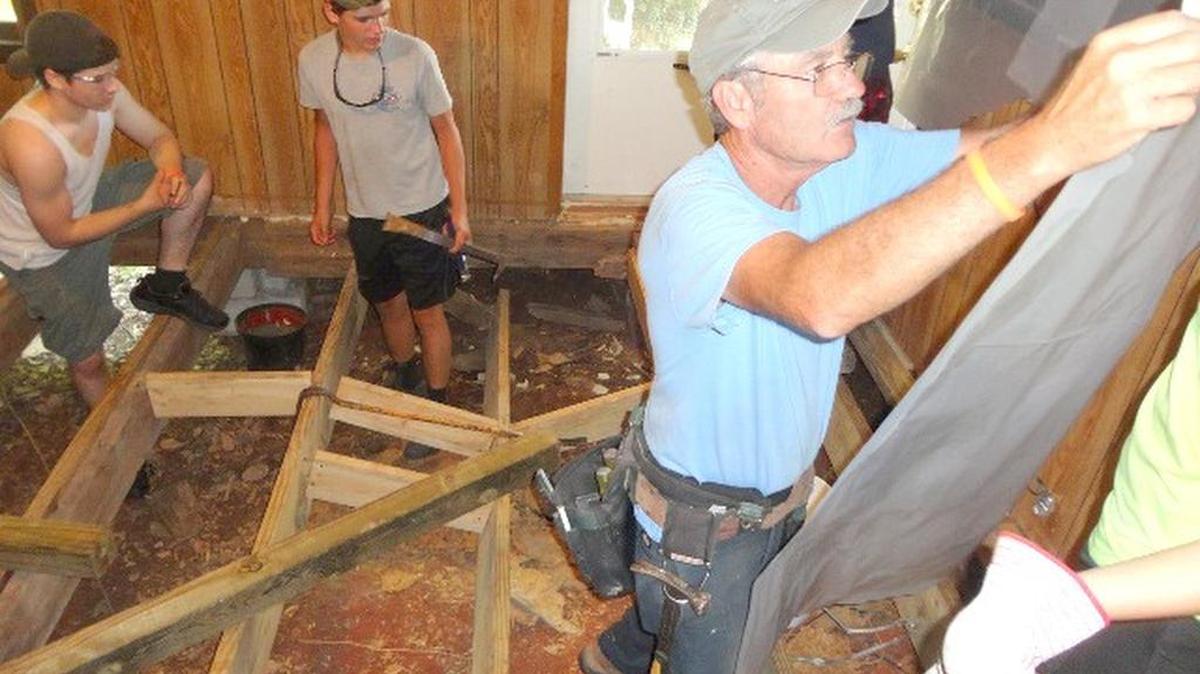 Tim Turbeville (right) directing campers on the complete replacement of a floor.