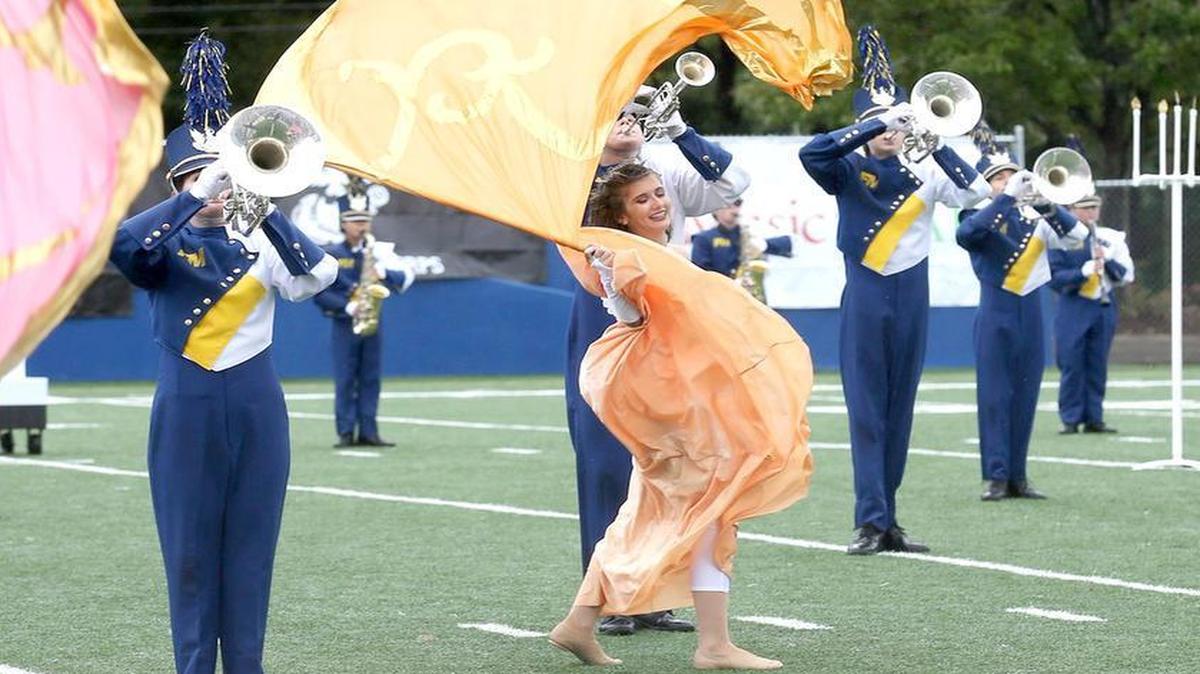 
Keturah Myers plays the mellophone as the fort Mill Band Color Guard spins flags beside her.
