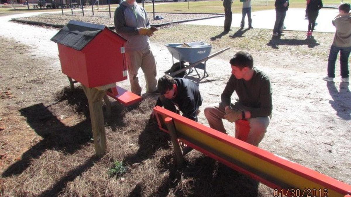 John Mark Trainer and his team work on the benches in front of the little free library at Bethel Elementary School.